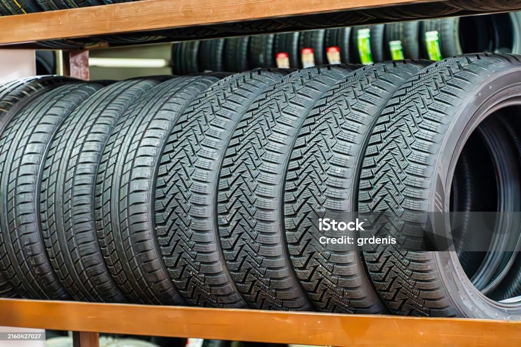 A Close Up Shot Of Several New Car Tires Stacked On A Shelf In A Store.